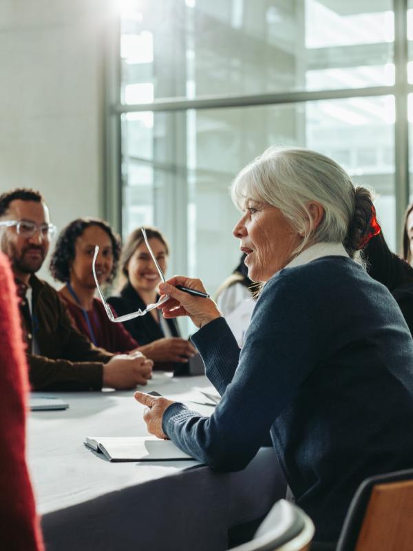 Personengruppe sitzt um einen Konferenztisch bei einer Schulung